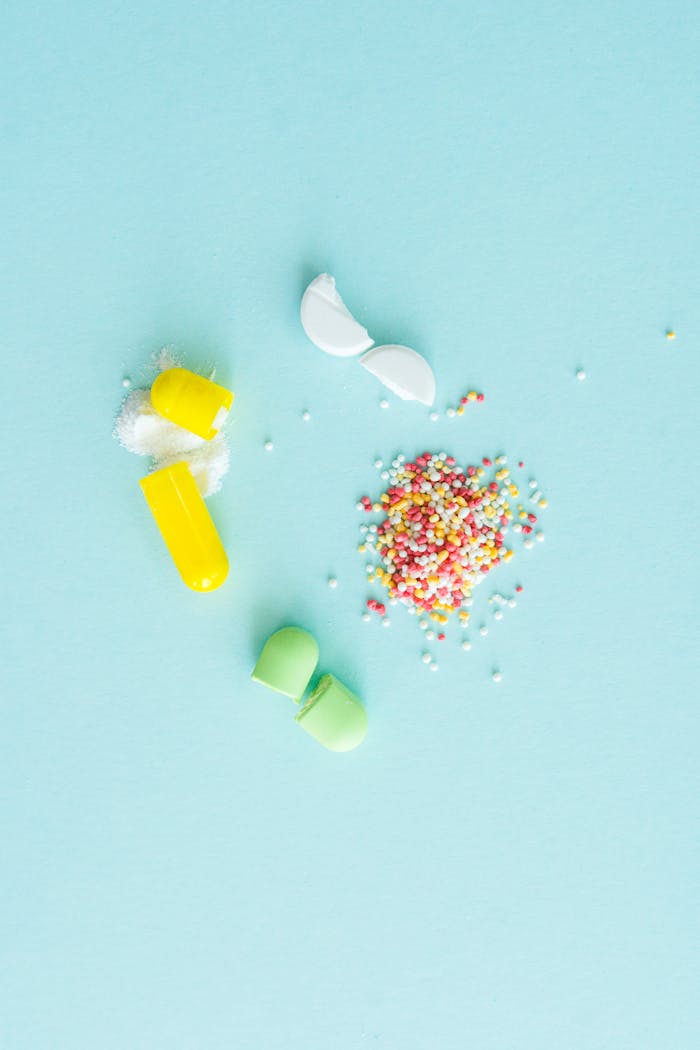 Flat lay of various capsules and tablets on a baby blue background, showcasing medical concepts.